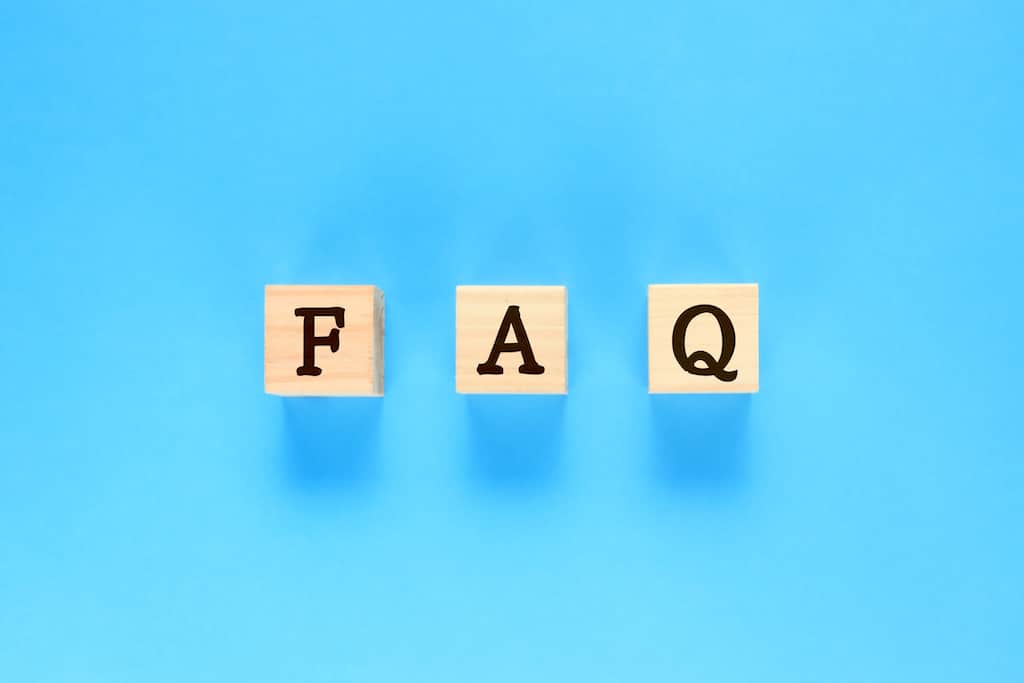 Blue background with wooden blocks spelling out FAQ. Representing questions about plumber frozen pipes.
