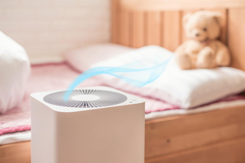 air purifier in bed room. air cleaner removing fine dust in house with teddy bear on bed. 