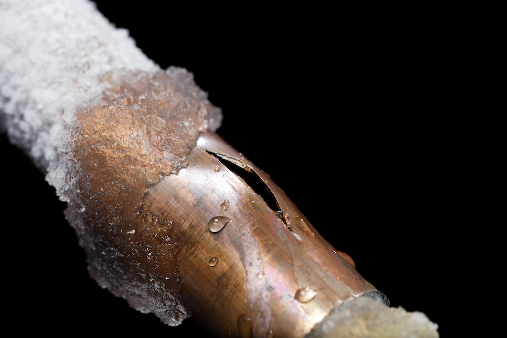 Frozen cracked pipe with black background. Plumber frozen pipes.