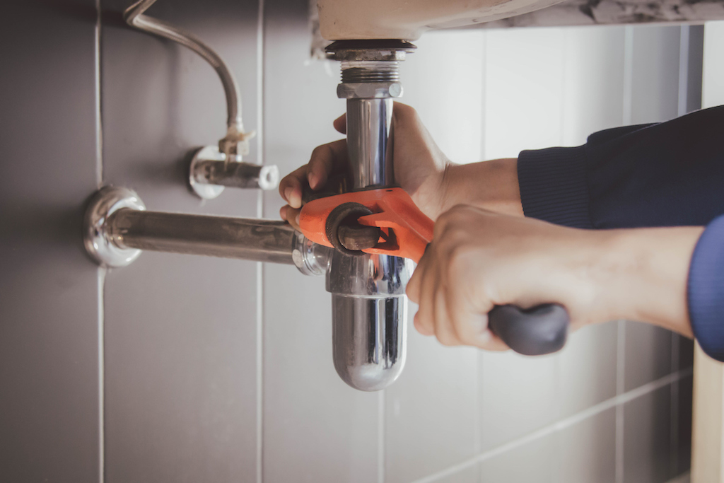 Plumber fixing sink with wrench. Plumbing services.