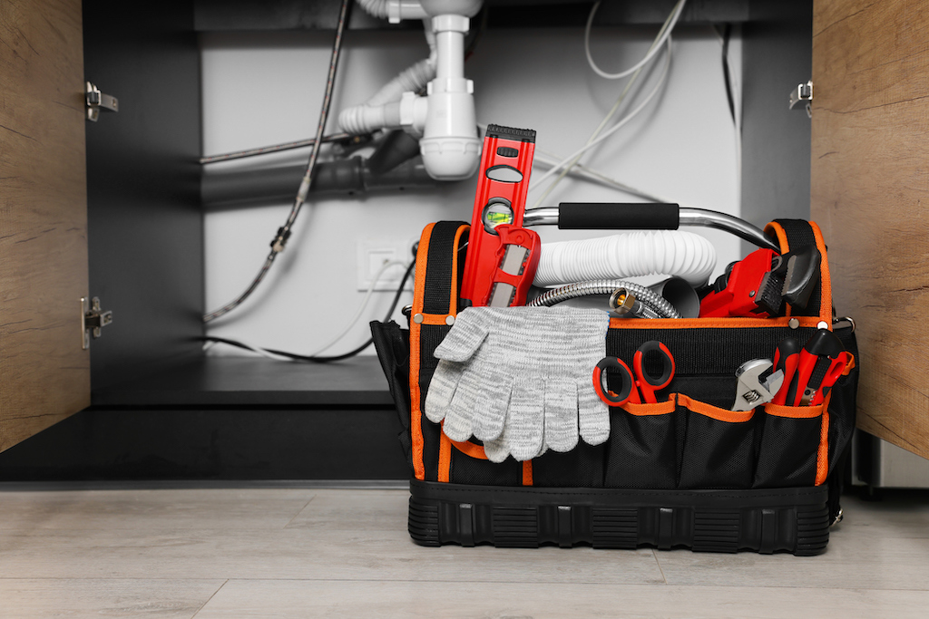 Plumbers bag with tools on the floor of the kitchen. | Plumbing service