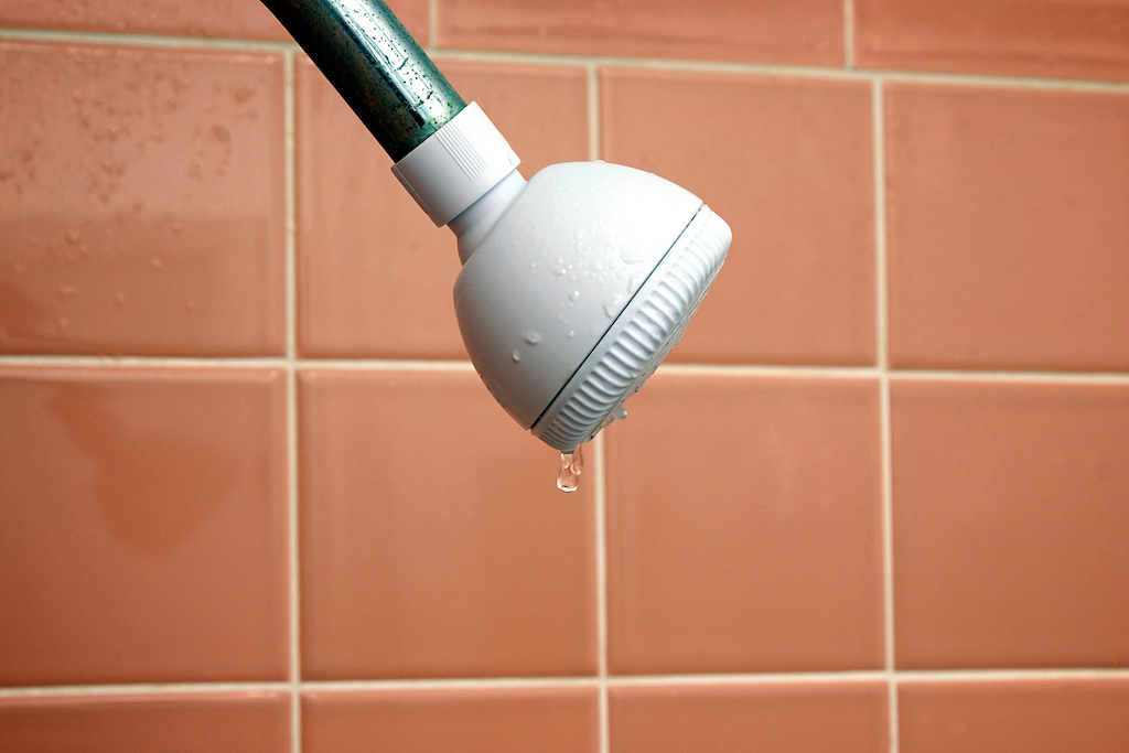 A dripping shower head in need of plumbing service.